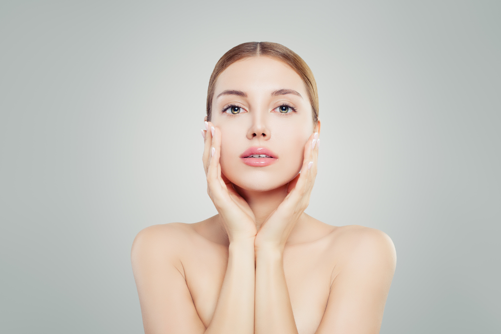 A woman with youthful, glowing skin gently touching her face, illustrating the effects of Peptide Therapy for Anti-Aging, promoting rejuvenation and a youthful appearance.